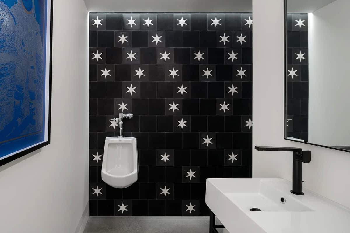 Lower-level bathroom with black and white star tile wall and modern wall-mounted sink