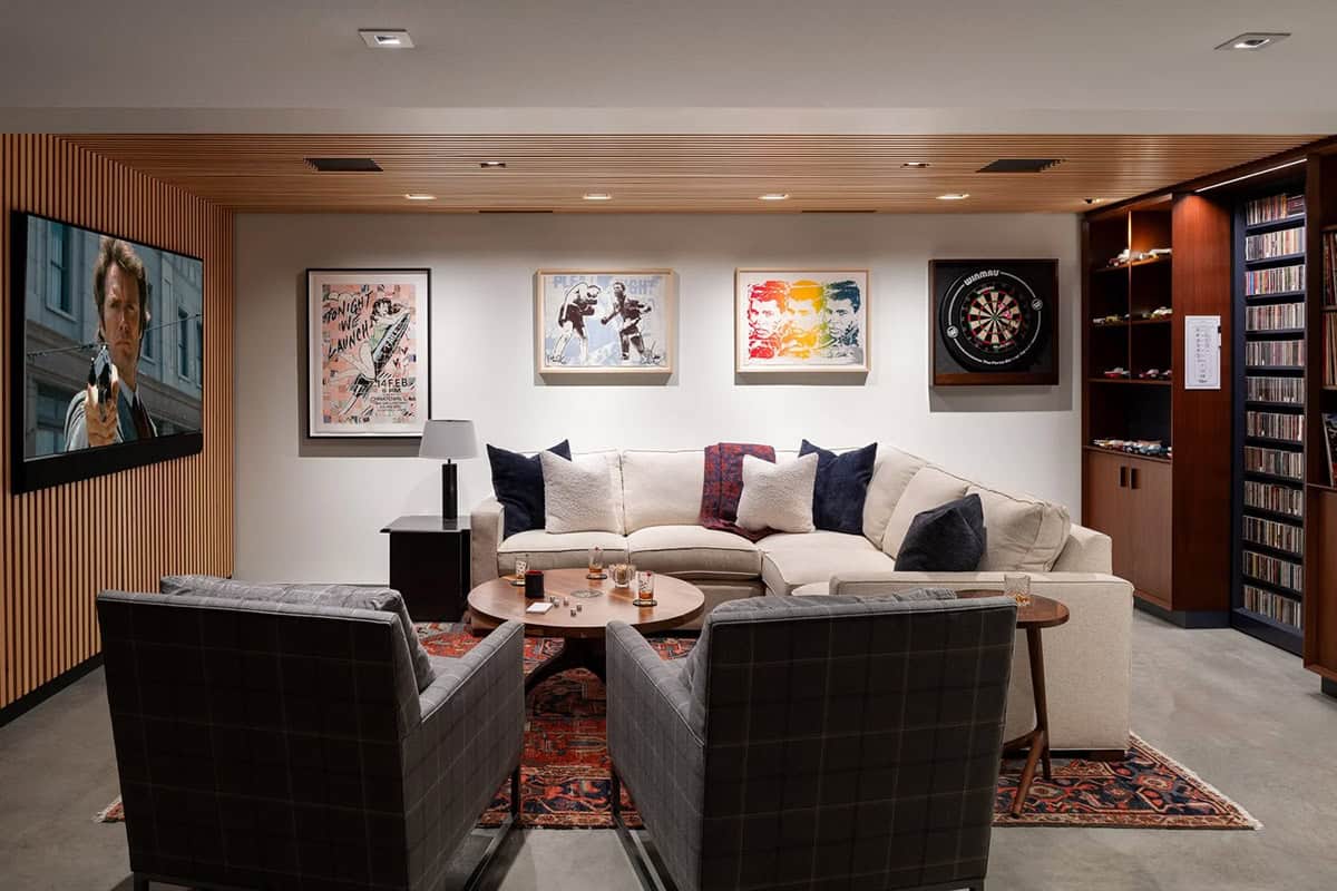 Lower-level lounge with sectional sofa, plaid armchairs, wood slat wall, and built-in media shelves