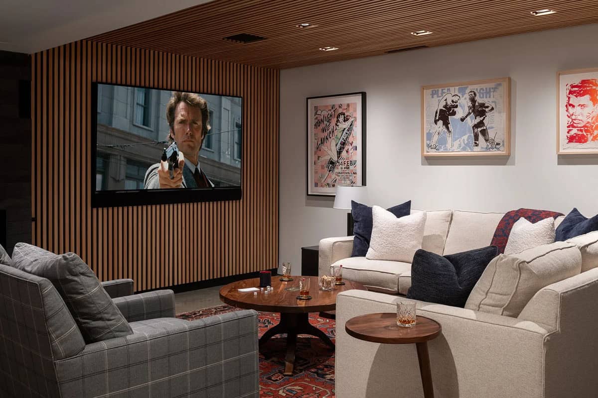 Media room with wall-mounted TV on a slatted wood wall, sectional sofa, and framed art