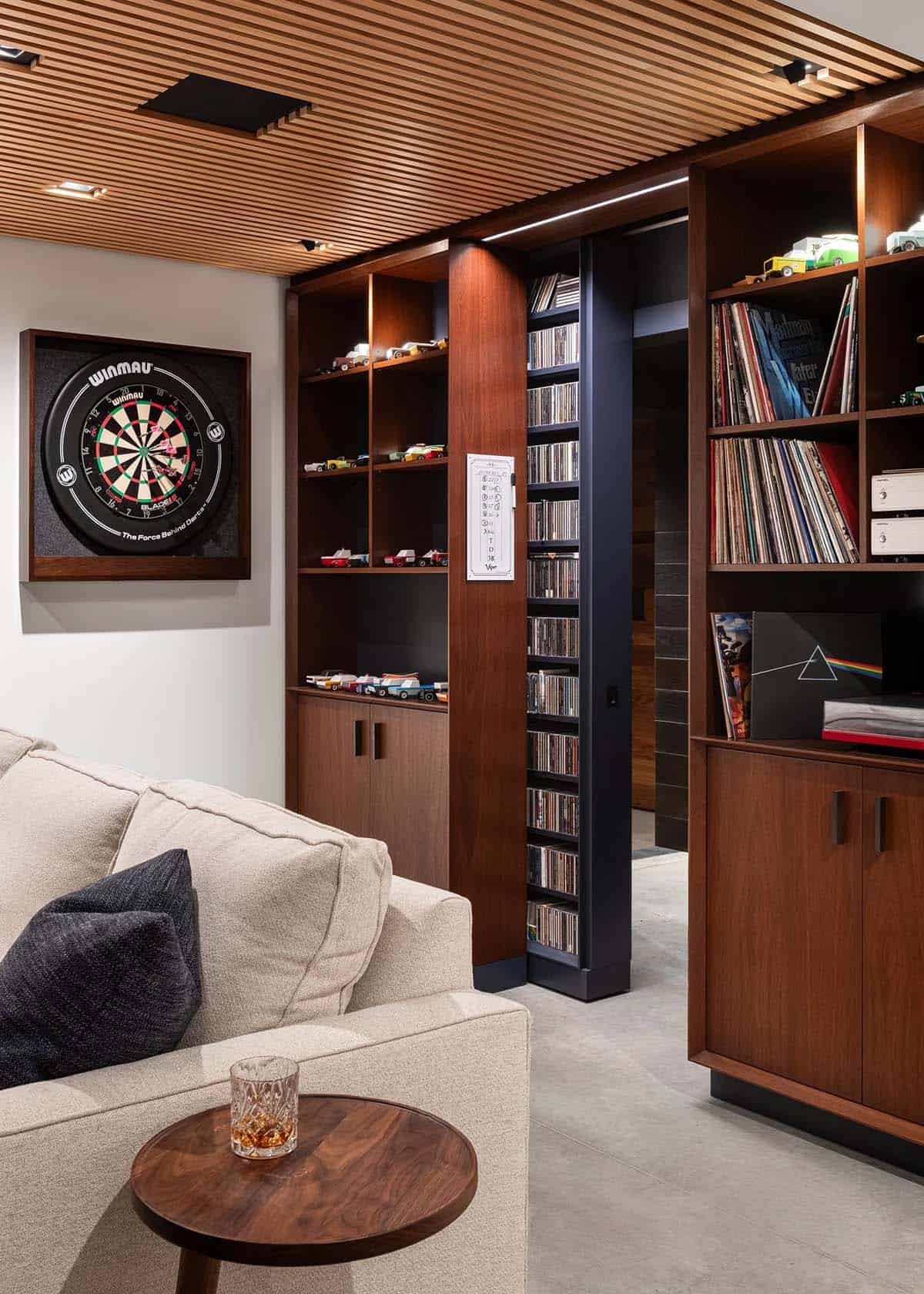 Built-in walnut shelving with pull-out CD storage, vinyl records, and dartboard