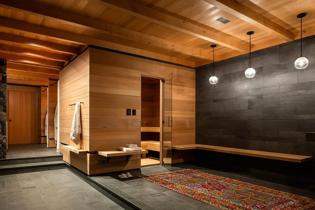 Spa area with wood-paneled sauna, dark textured wall, glass pendant lights, and stone floor