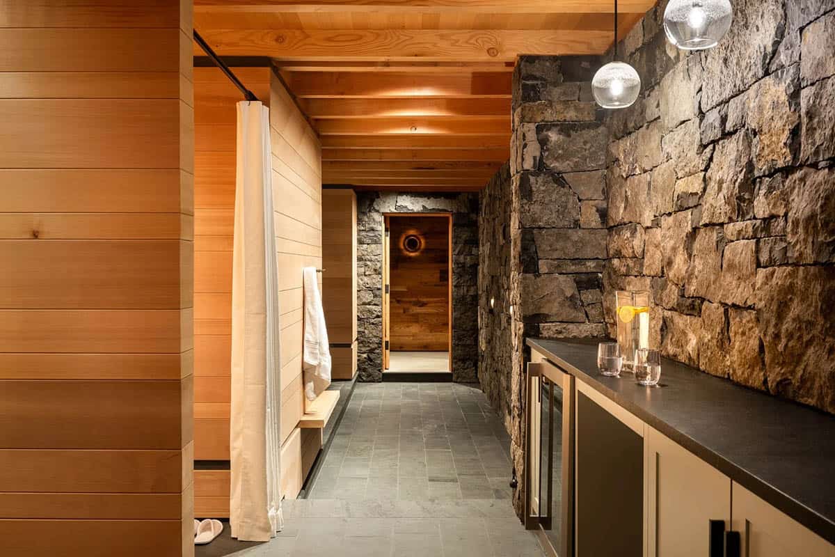 Spa corridor with fieldstone walls, glass pendants, and a dark counter with beverage fridge