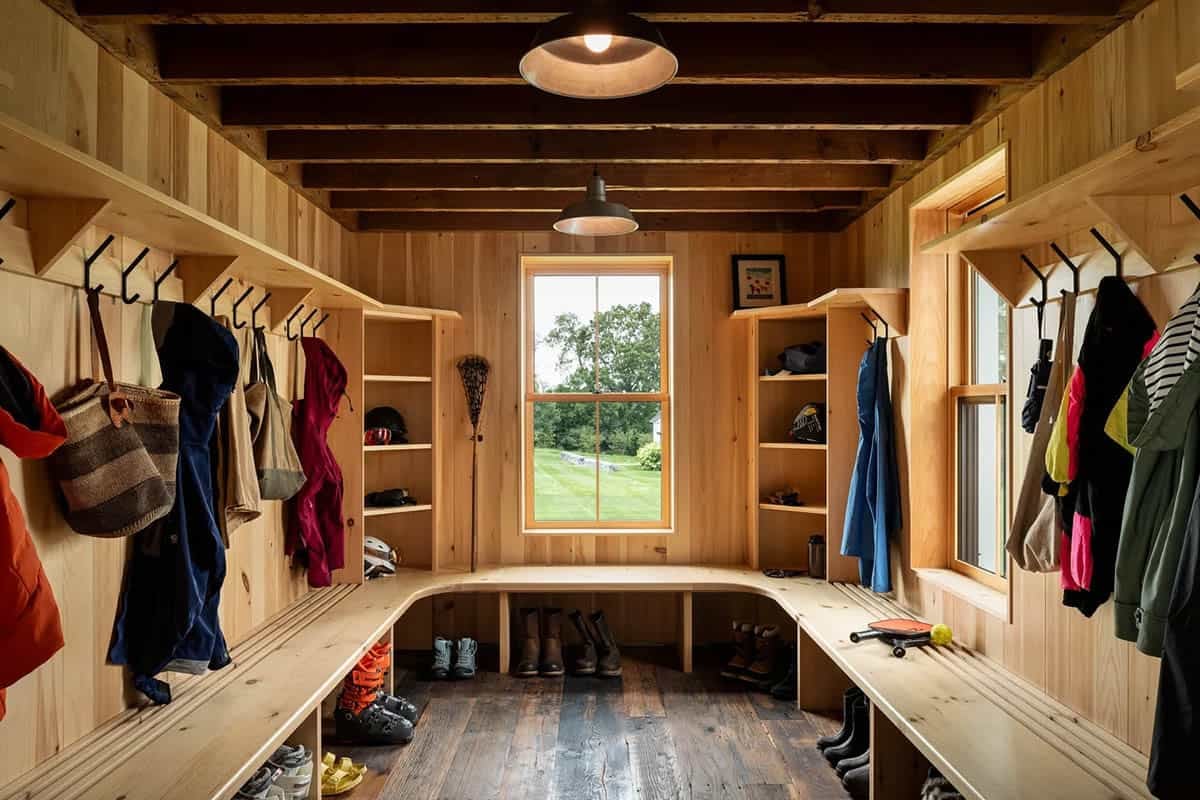 Reclaimed post and beam garage mudroom with pine walls, built-in benches, and coat hooks