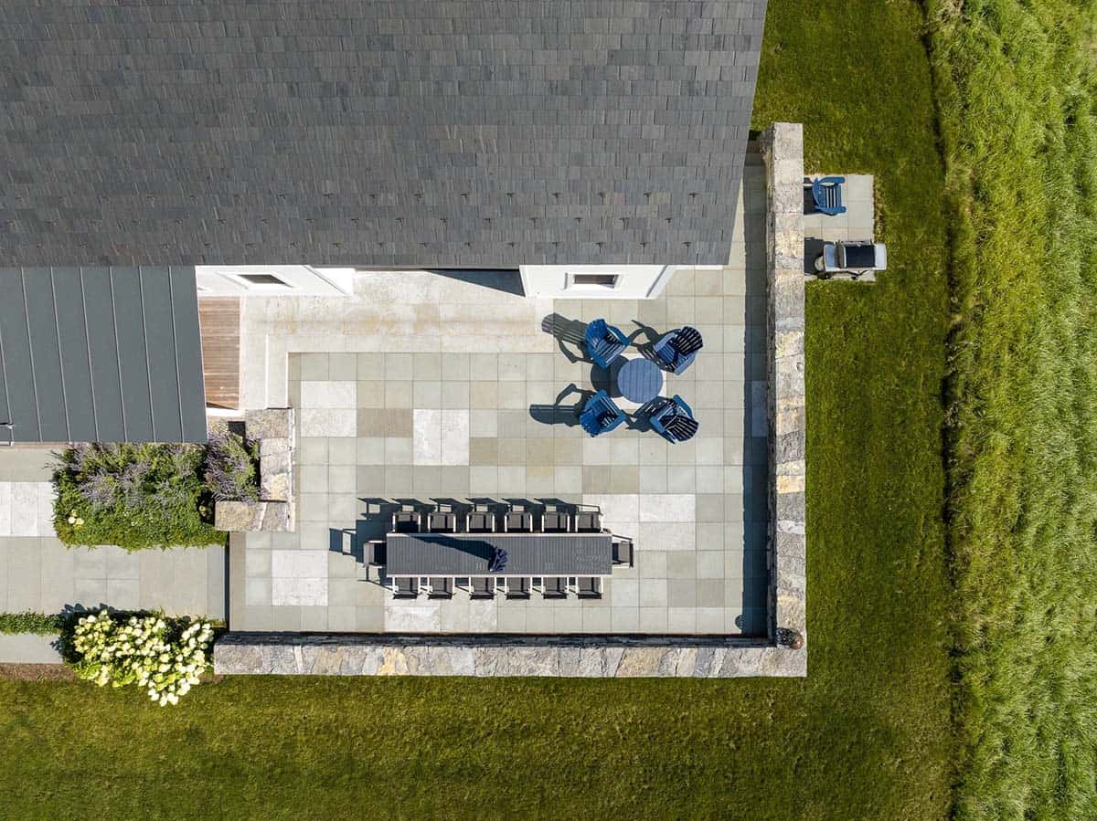 Aerial view of bluestone patio with long dining table, Adirondack chairs, and fieldstone wall
