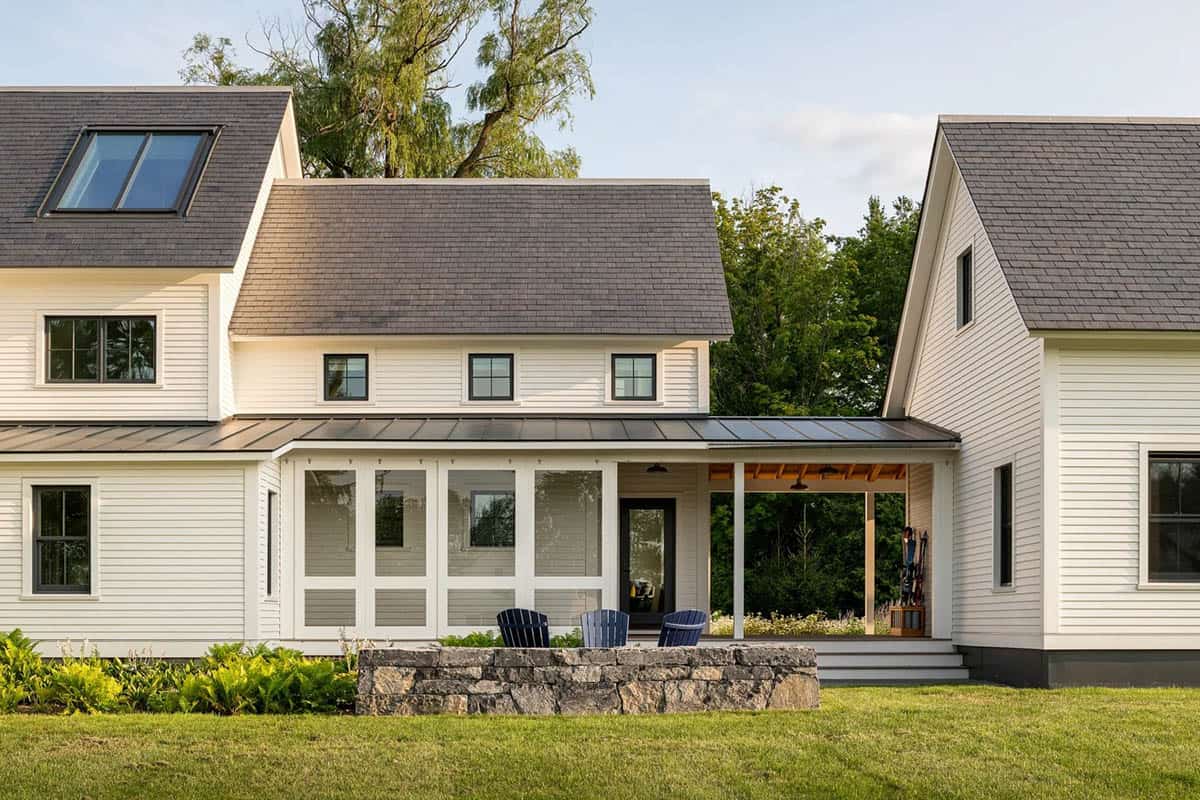 Covered breezeway and screened porch connecting the main house and garage wing, with stone wall and Adirondack chairs