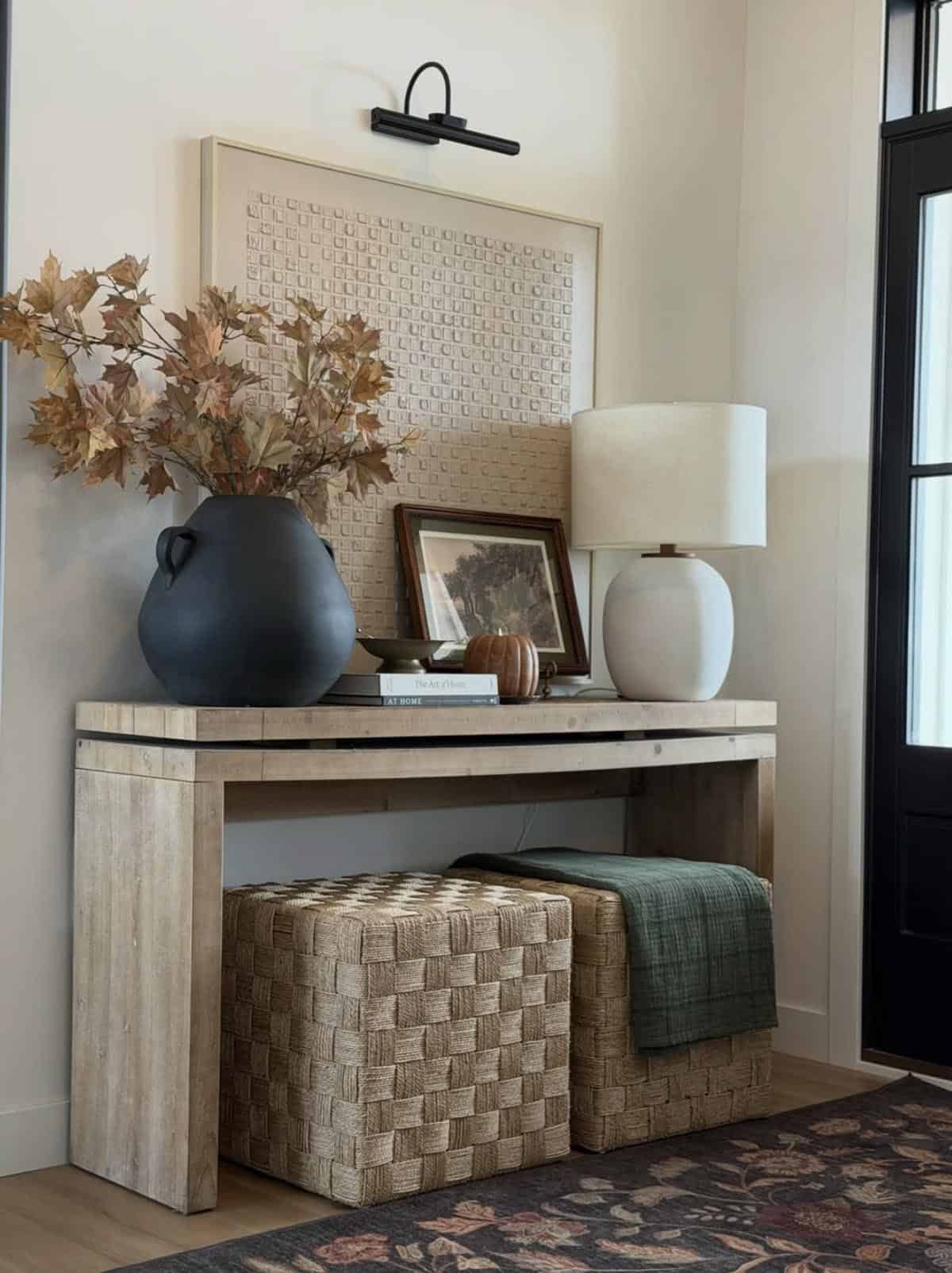 Entryway console table with a black vase and a patterned rug below