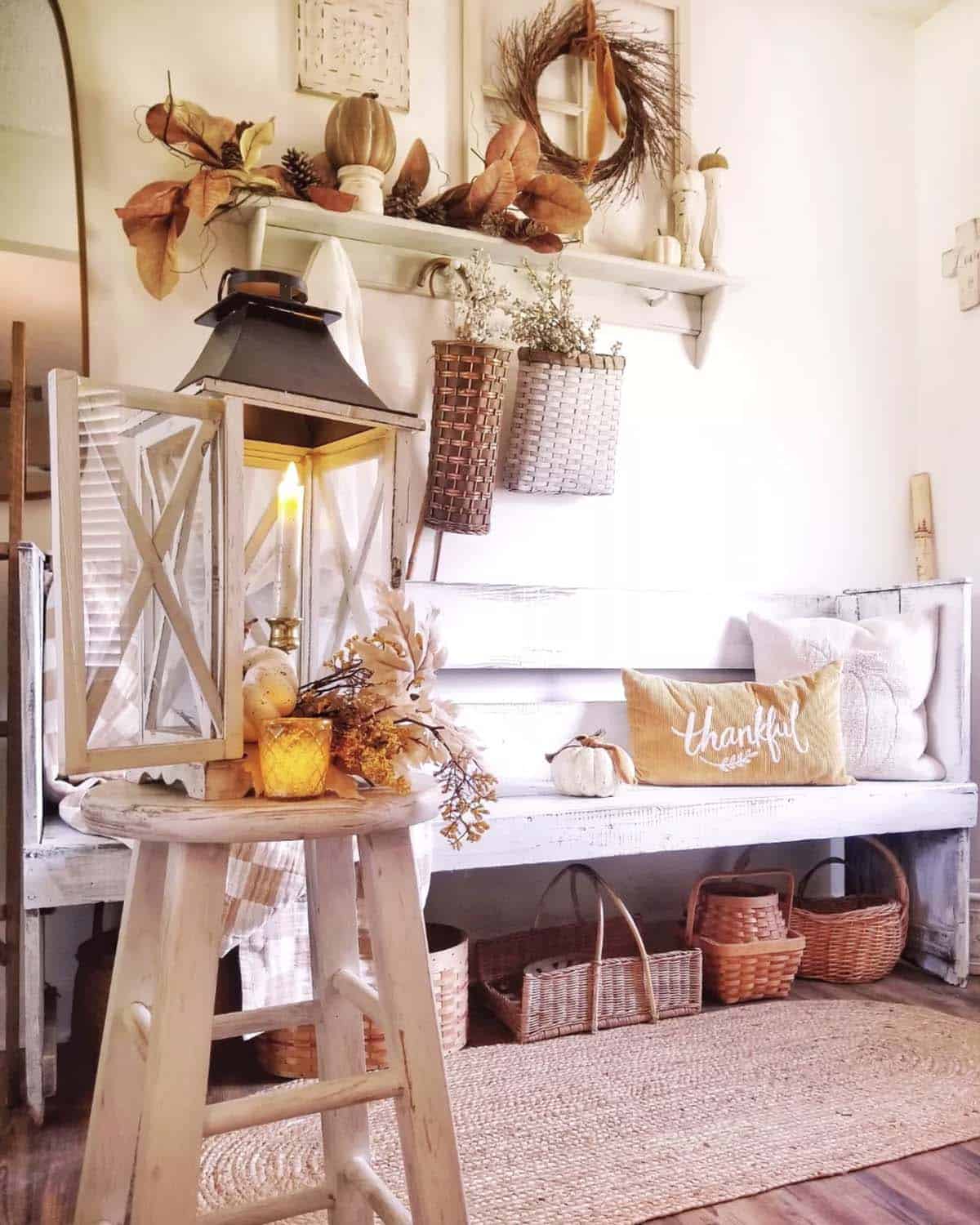 Wood lantern with a candle on a stool beside a farmhouse entryway bench