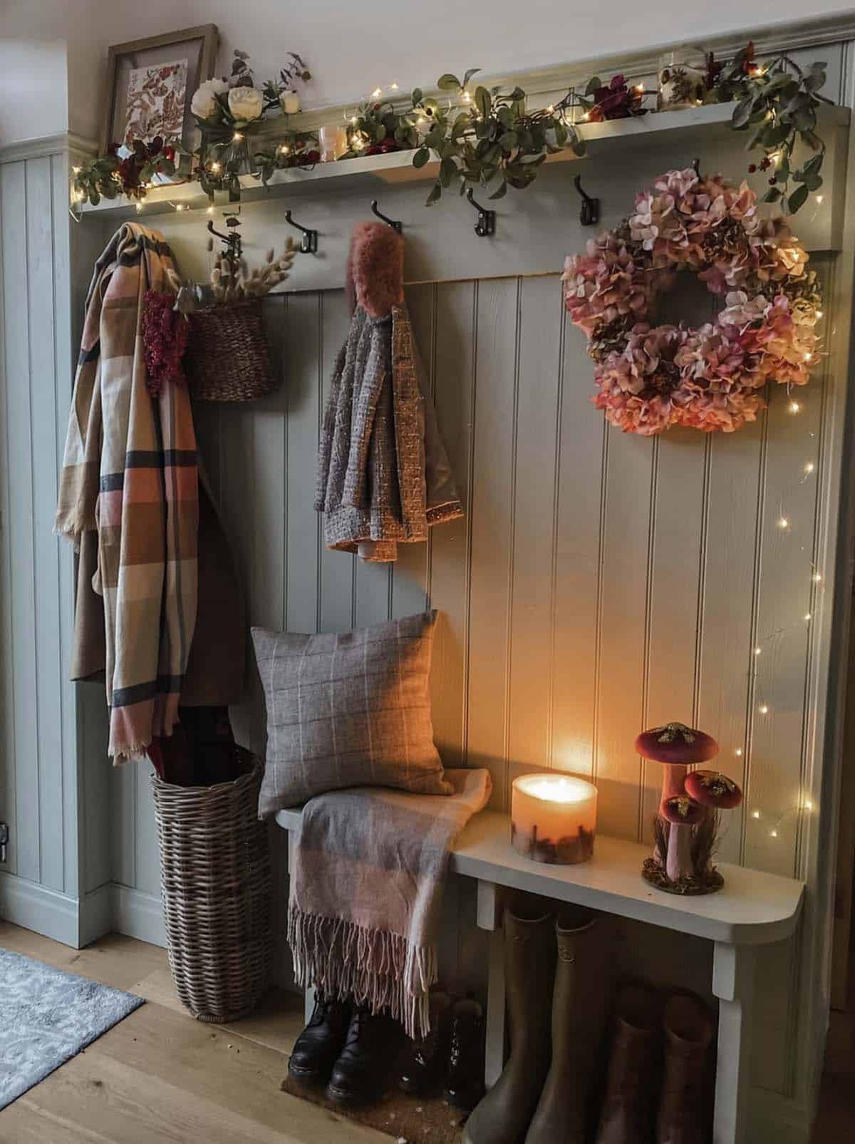 Green paneled mudroom entry with string lights and a pink hydrangea wreath