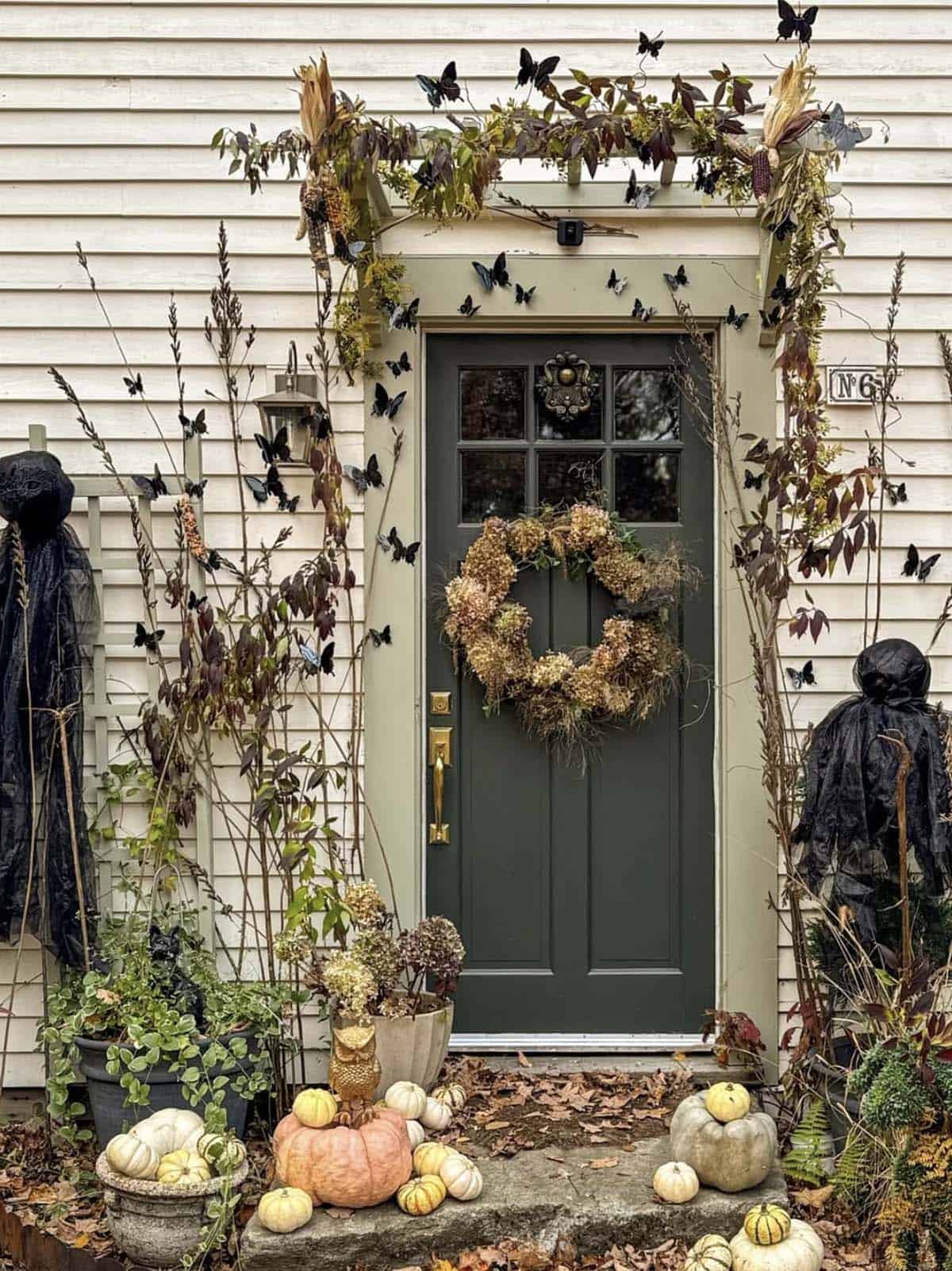 Fall front door with dried hydrangea wreath, foraged branches, and muted pumpkins