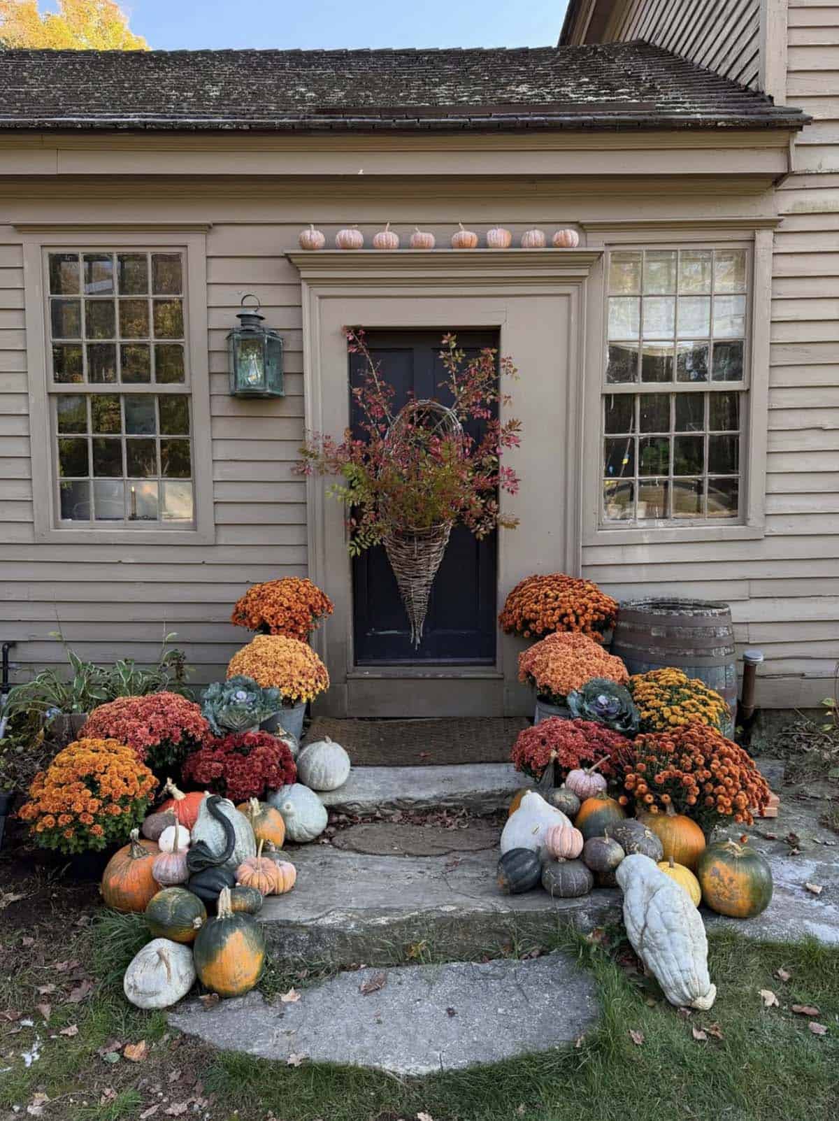 Fall mums and heirloom pumpkins on stone steps below a black door