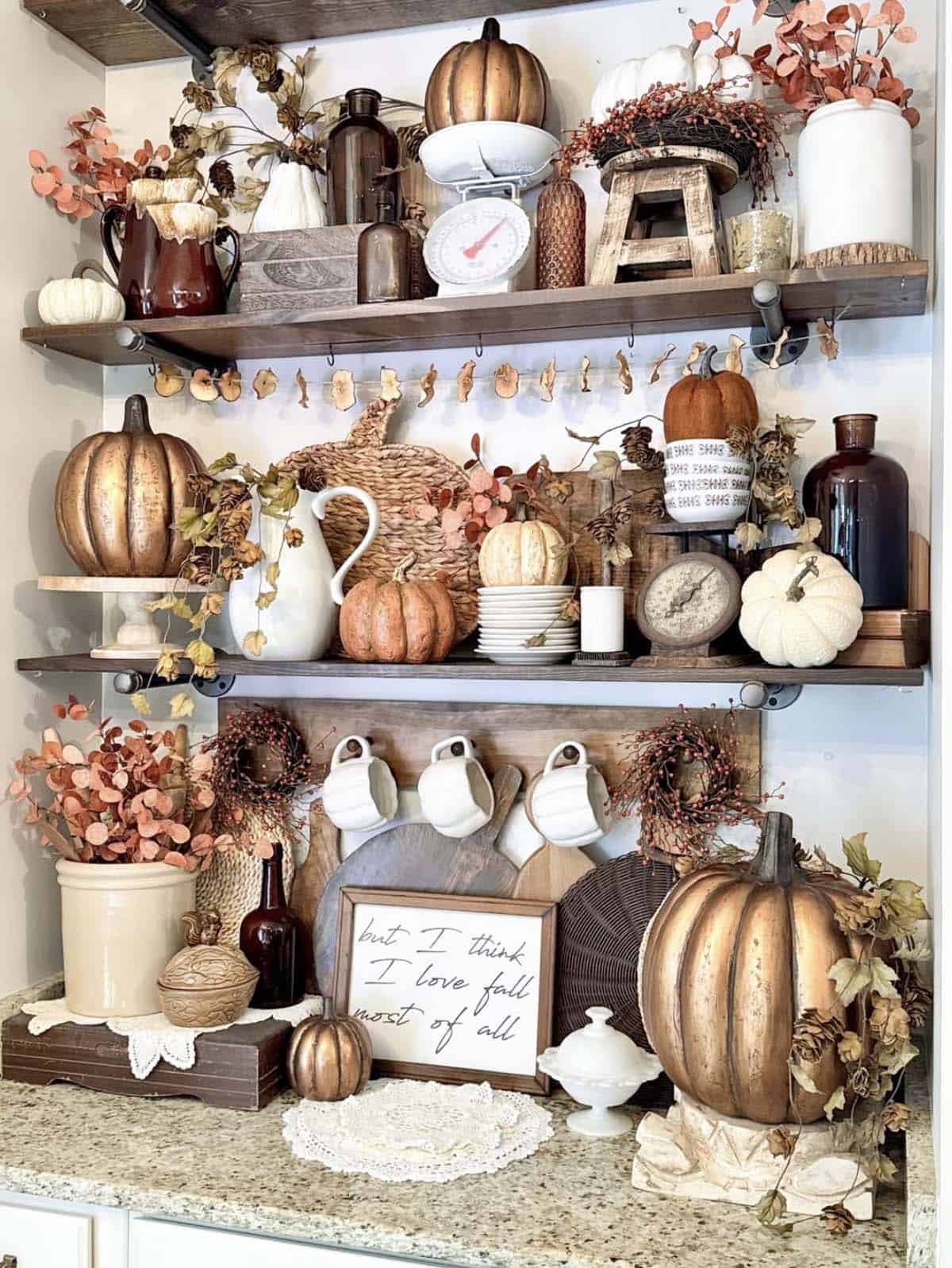 Open kitchen shelves layered with pumpkins, dried florals, and vintage kitchen finds