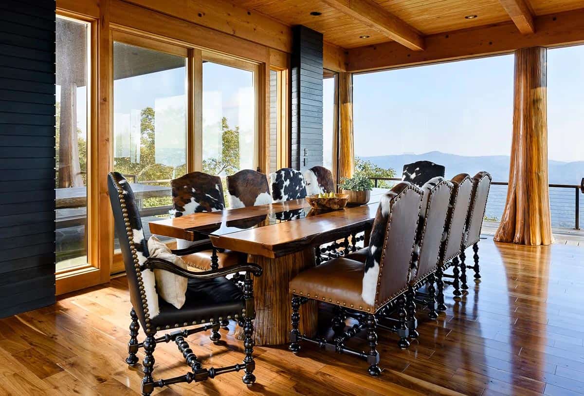 Dining table with cowhide upholstered chairs beneath tree trunk columns