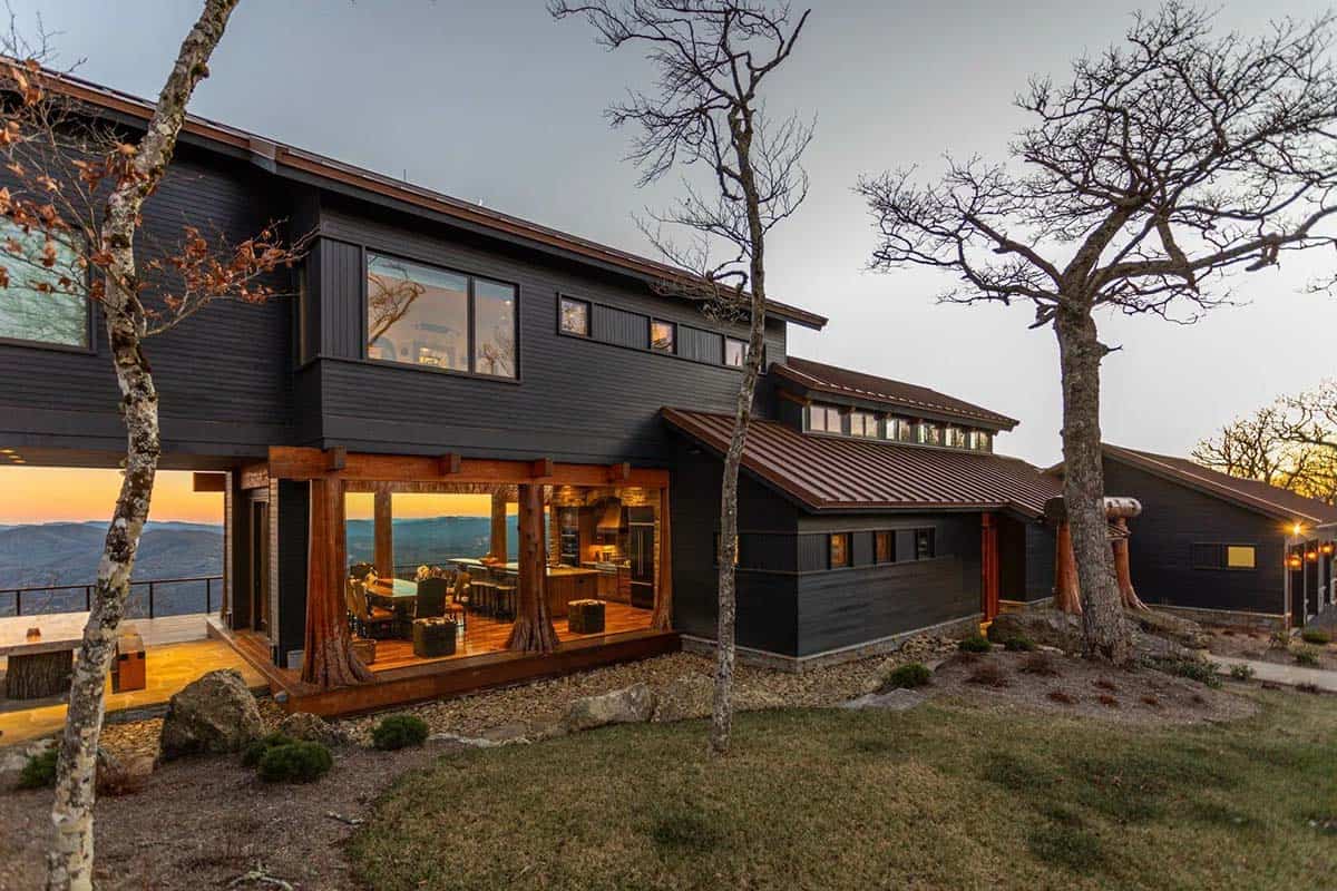 Timber home glows at sunset above a mountain valley view