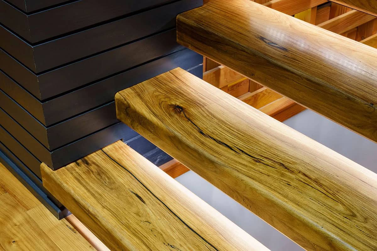 Close up of live edge wood stair treads against black paneling