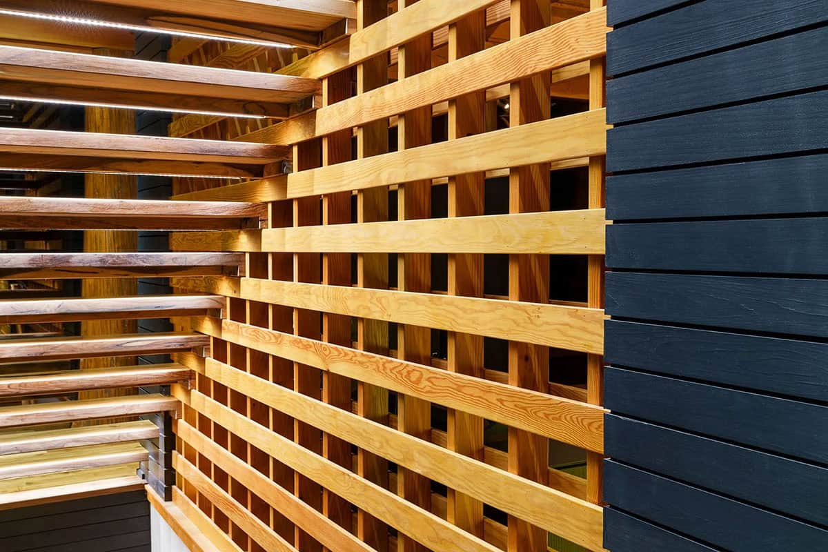 Wood lattice screen detail beside a black shiplap interior wall