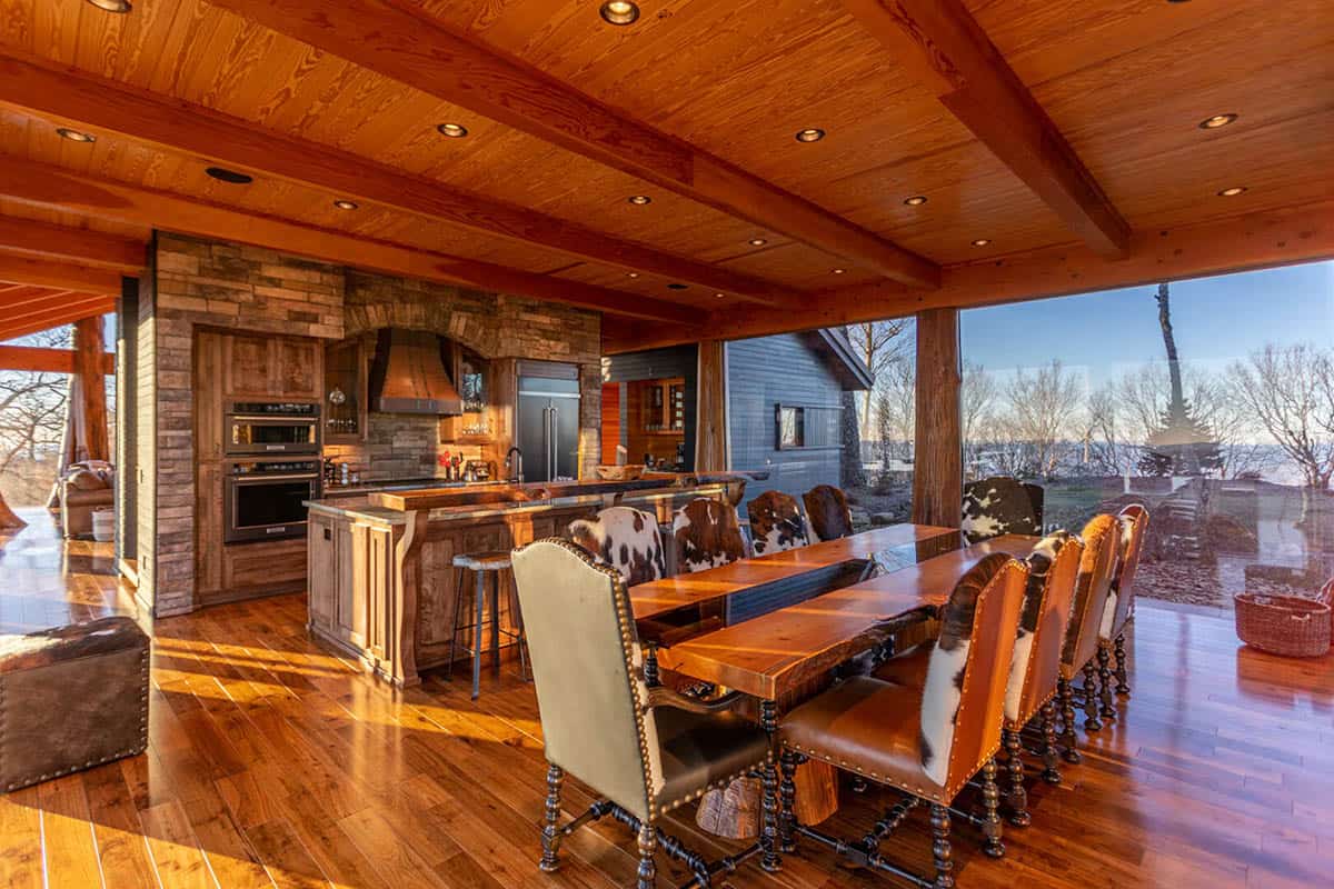 Dining table with cowhide chairs beside a stone kitchen island