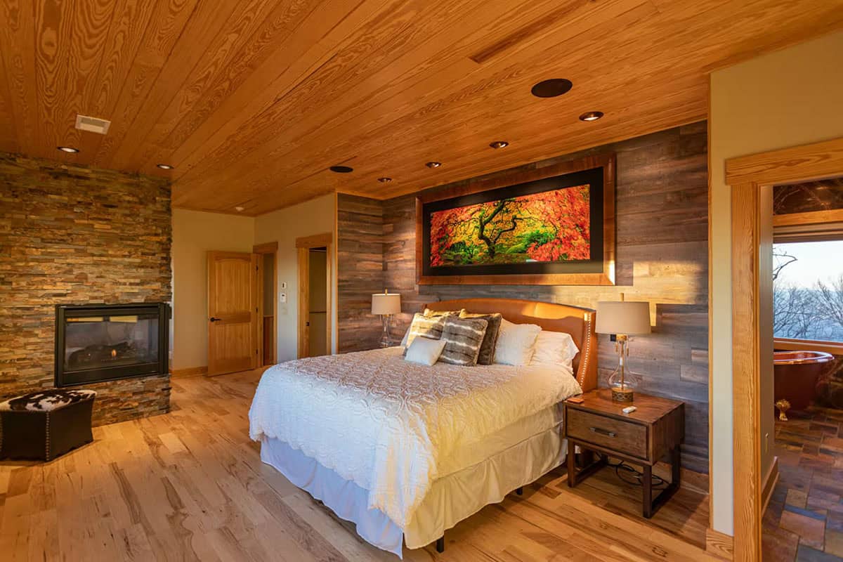 Primary bedroom with stone fireplace and artwork above the bed