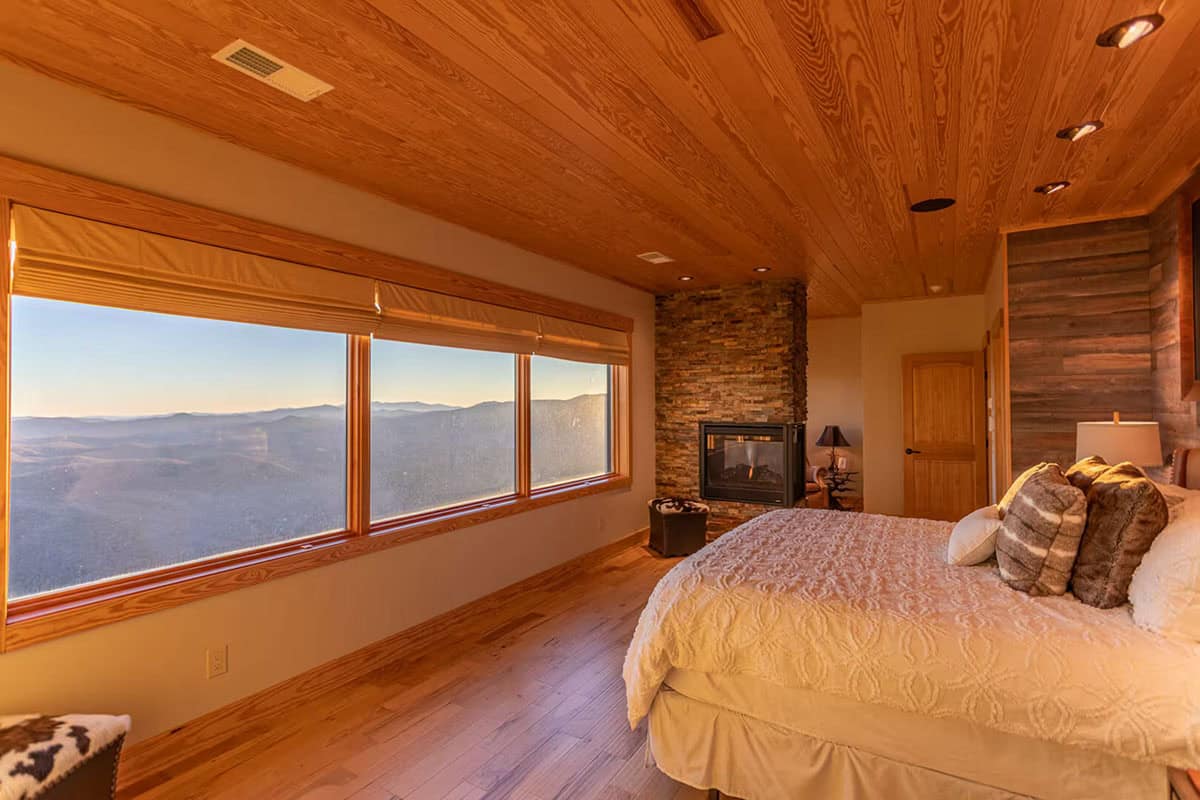 Primary bedroom window seat framed by a stone fireplace nook