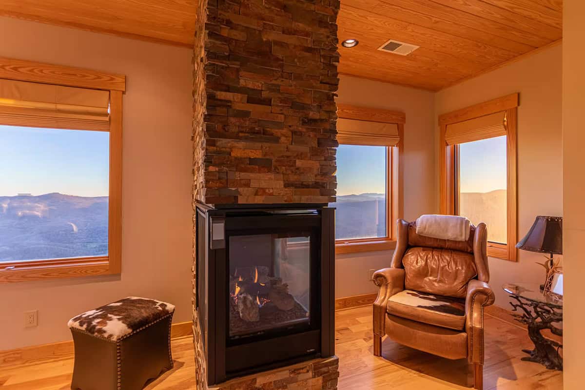 Double sided stone fireplace between two mountain view sitting areas