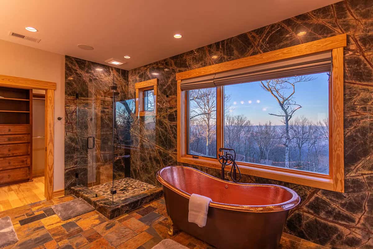 Primary bathroom with copper soaking tub and marble tiled walls