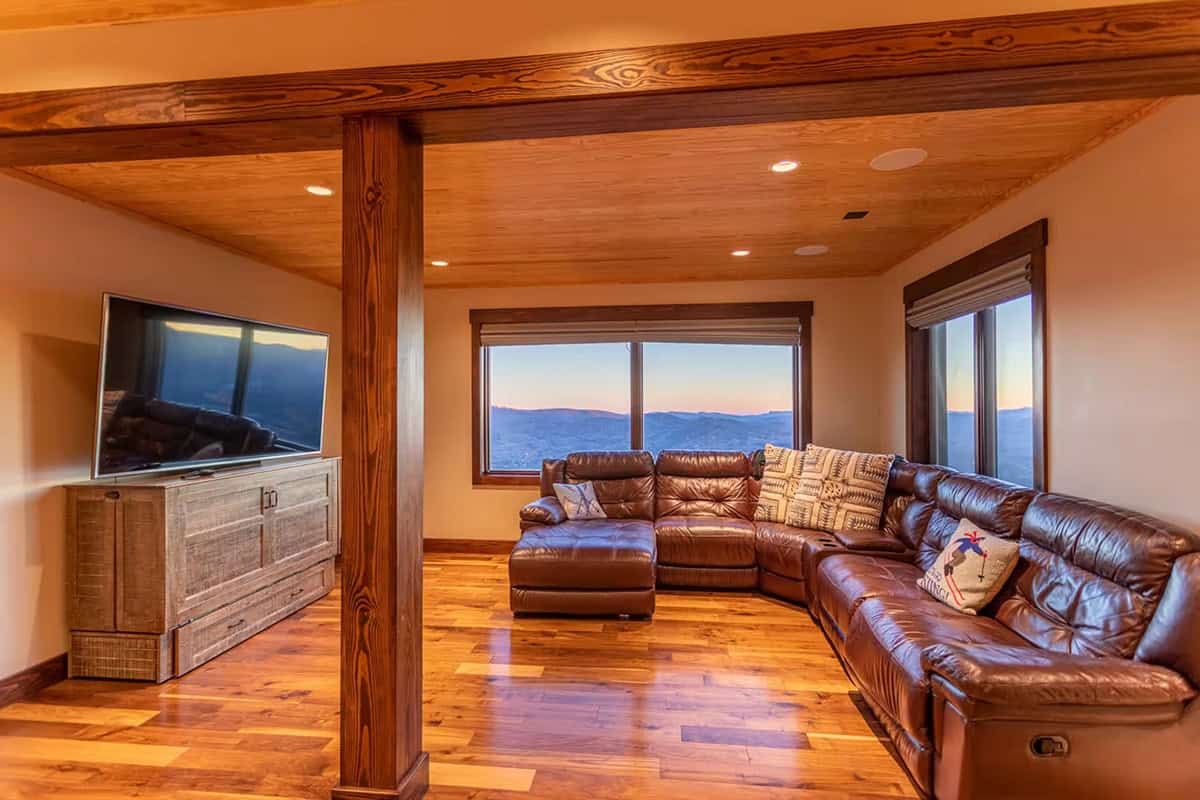 Media room with leather sectional and mountain view windows