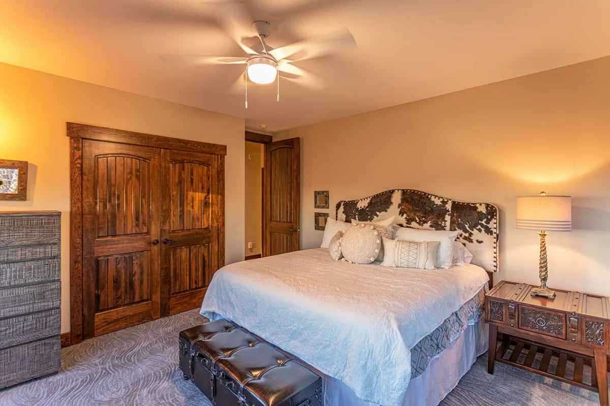 Guest bedroom with cowhide headboard and dark wood doors