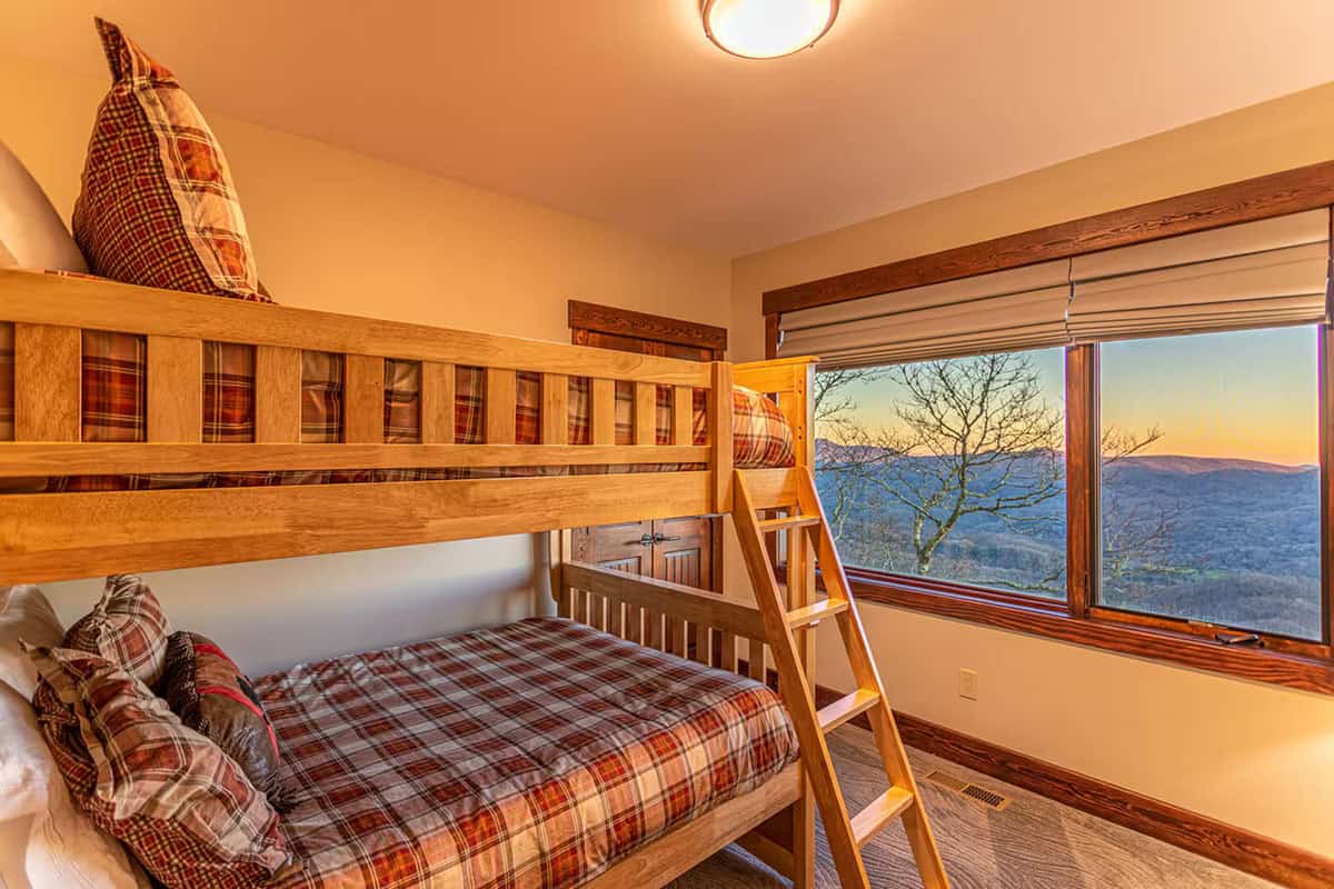Bunk bedroom with plaid bedding and a mountain view window