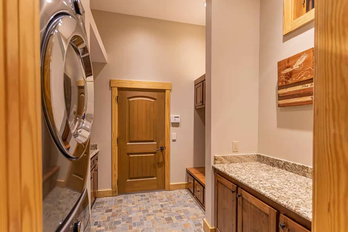 Mudroom with granite counter, wood door, and stacked laundry machines