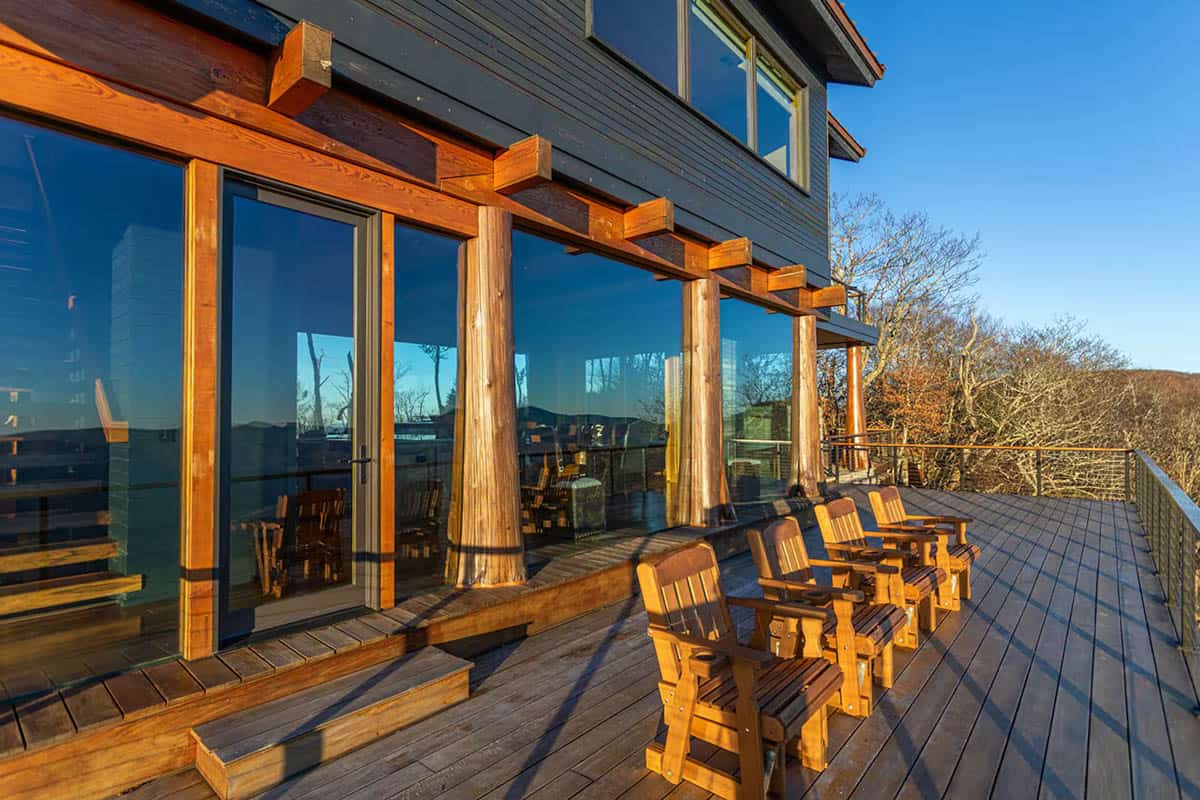 Deck with wooden armchairs along a glass walled dining room