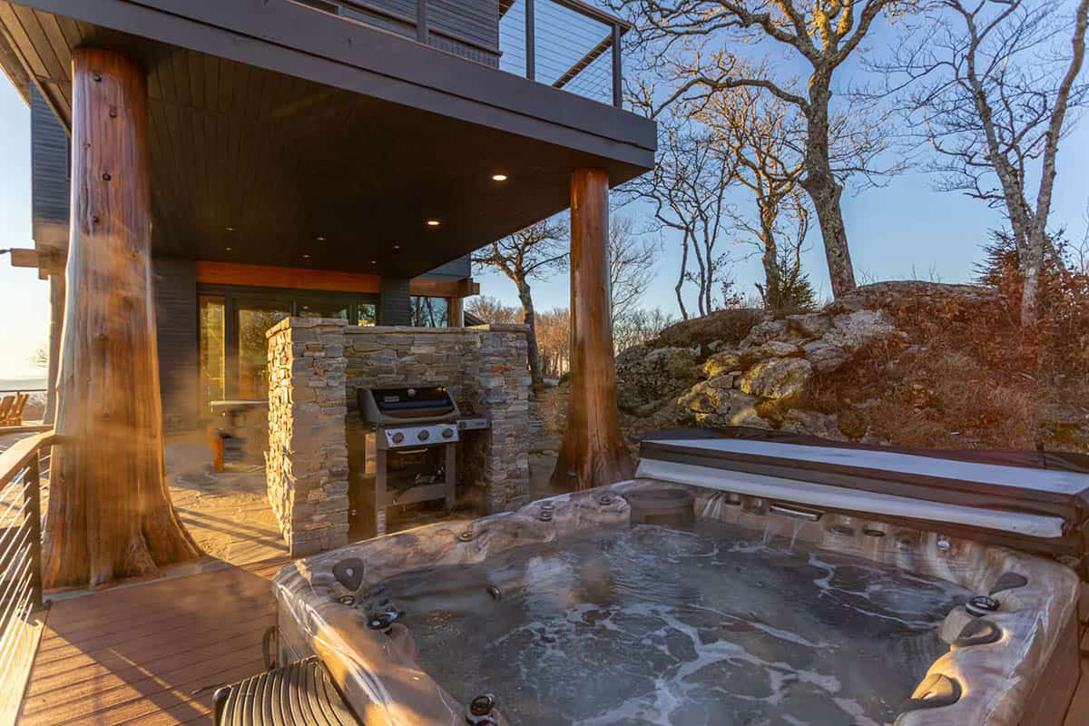 Hot tub beside a stone outdoor kitchen with a built in grill