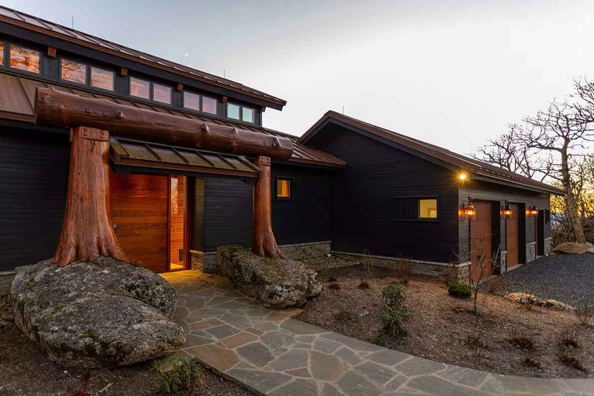 Timber portal entrance framed by tree trunk columns at dusk
