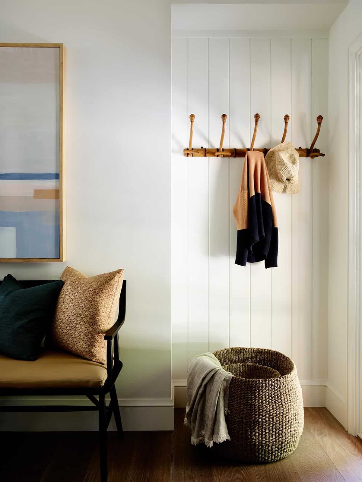 Entry nook with vintage wood coat rack, woven basket, and black bench