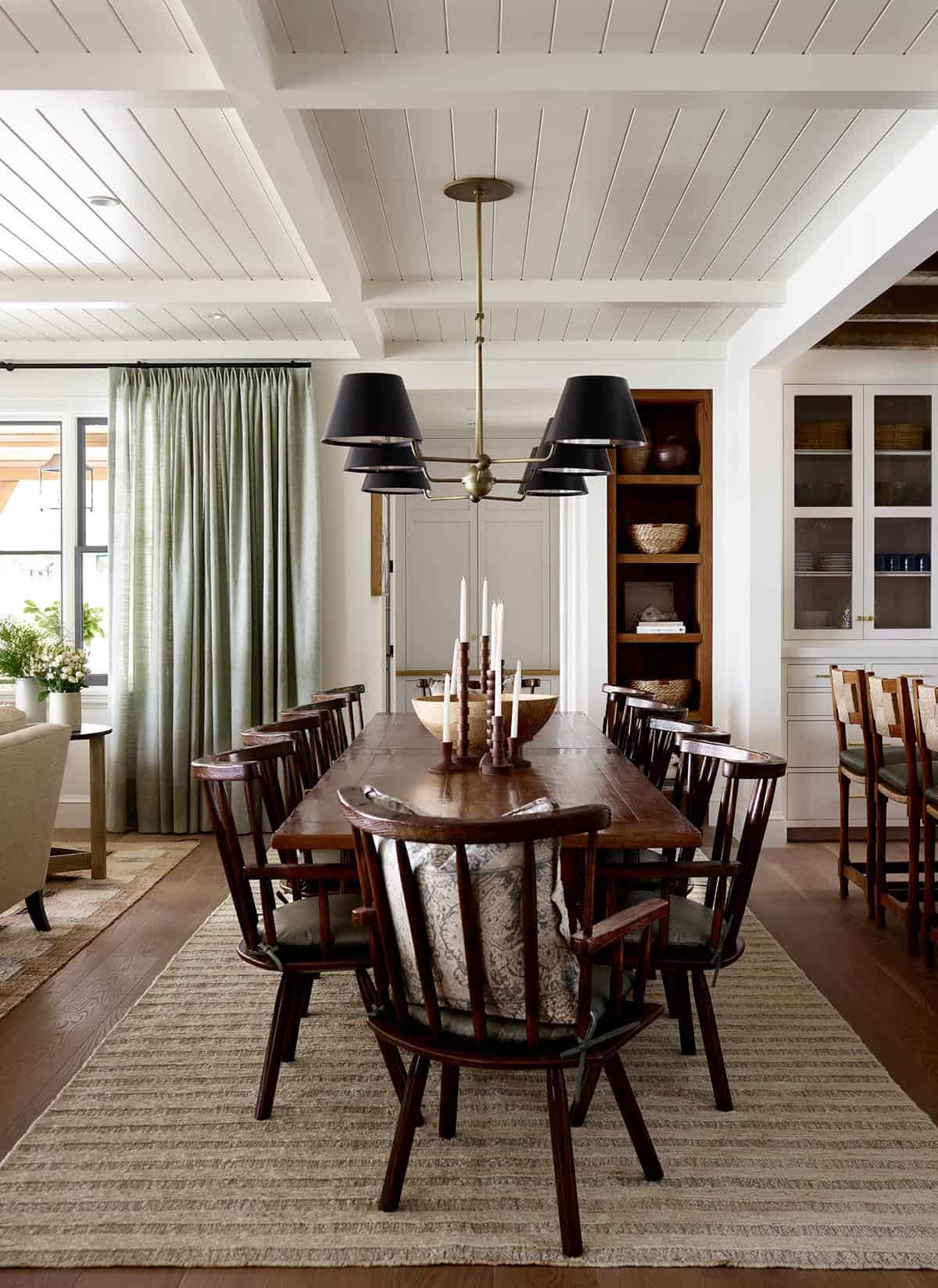 Dining room with long wood table, spindle chairs, and black shade chandelier