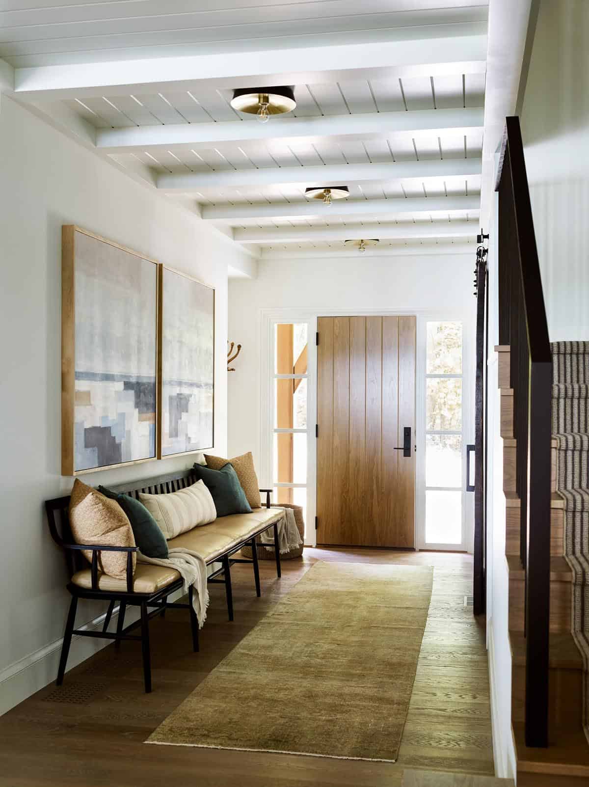 Entry hall with wood front door, bench, and beamed shiplap ceiling