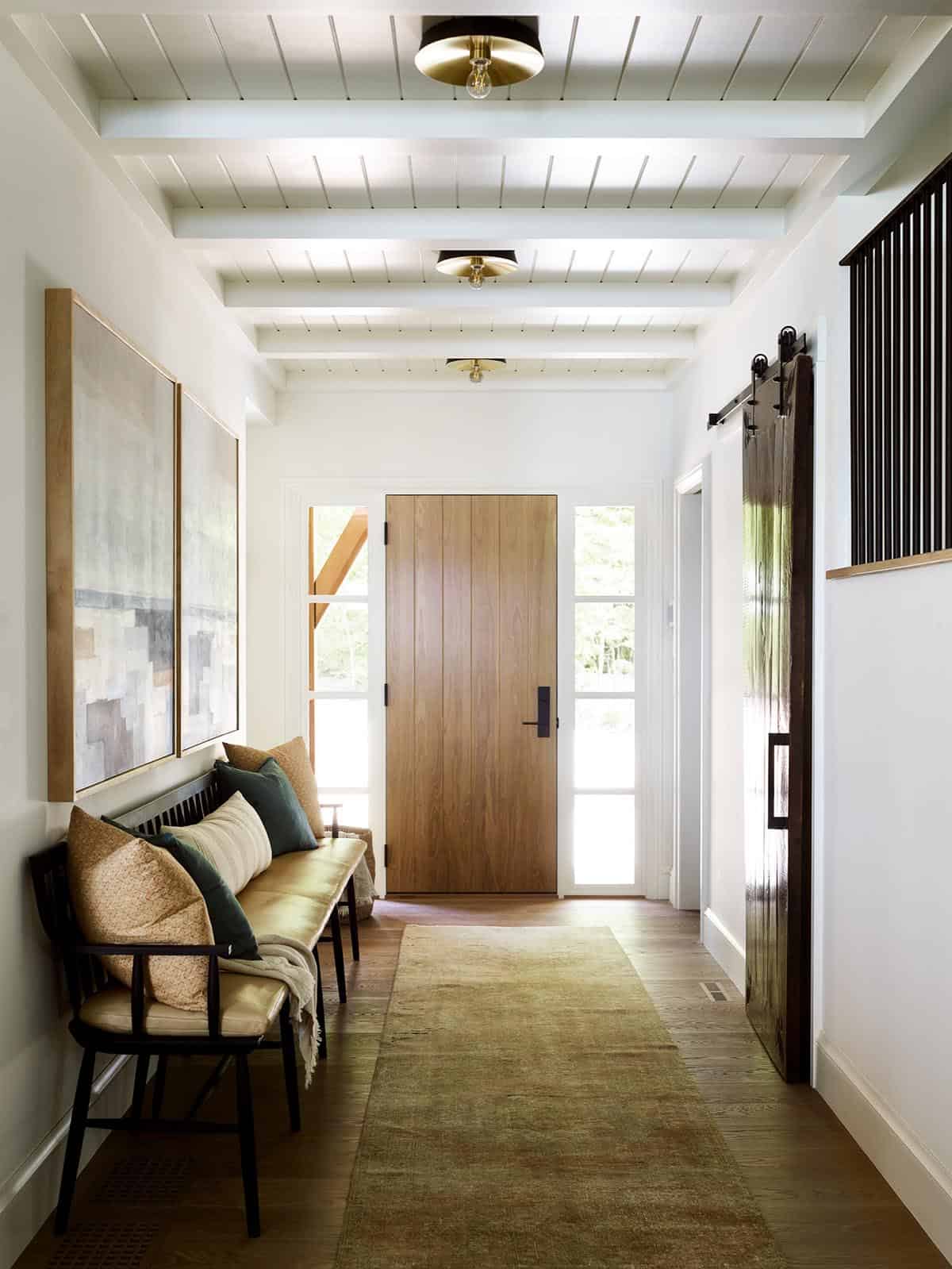 Hallway to front door with runner rug, sliding barn door, and brass flush mounts