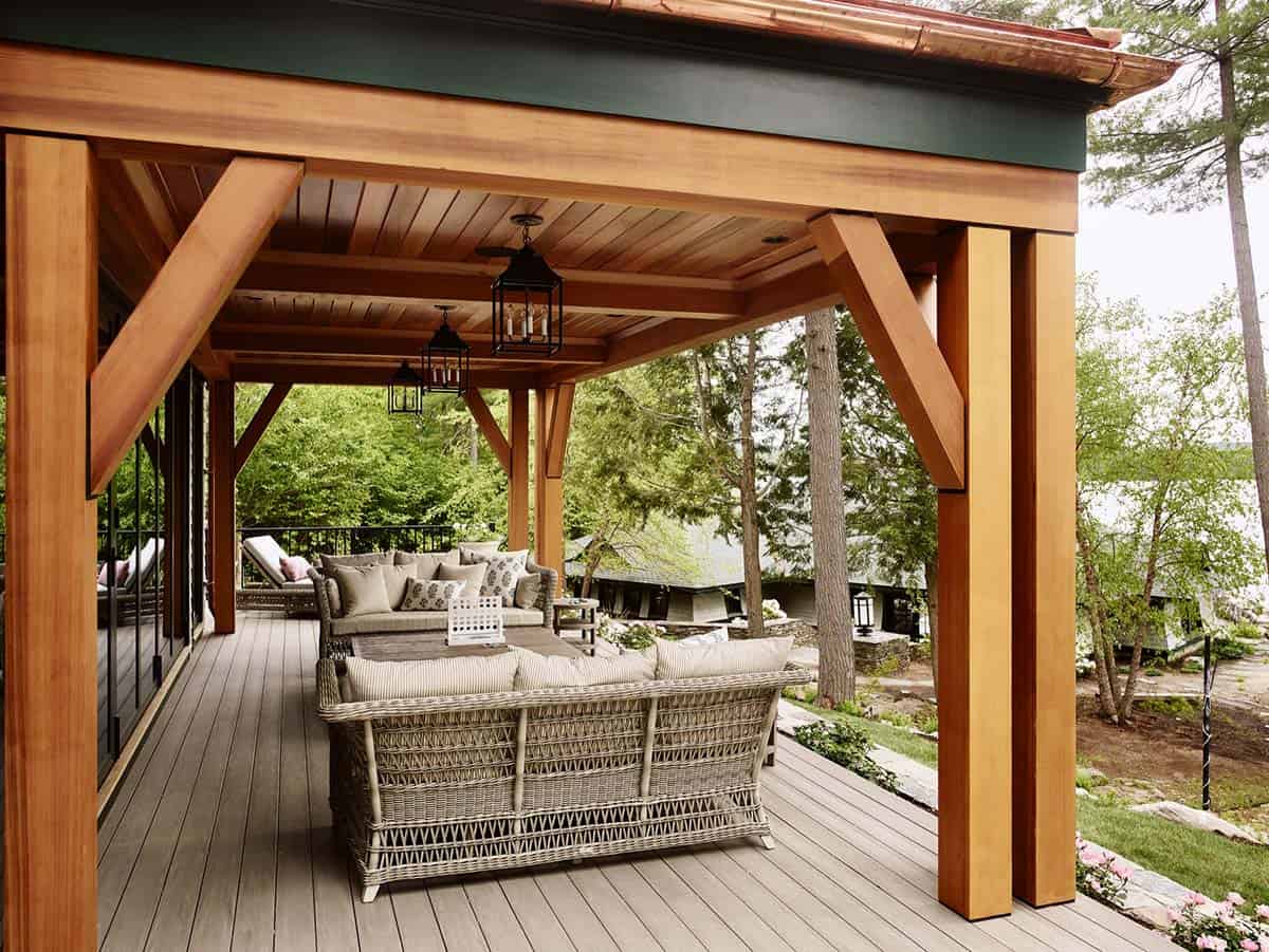 Covered lakeside porch with timber posts, wicker seating, and lantern lights