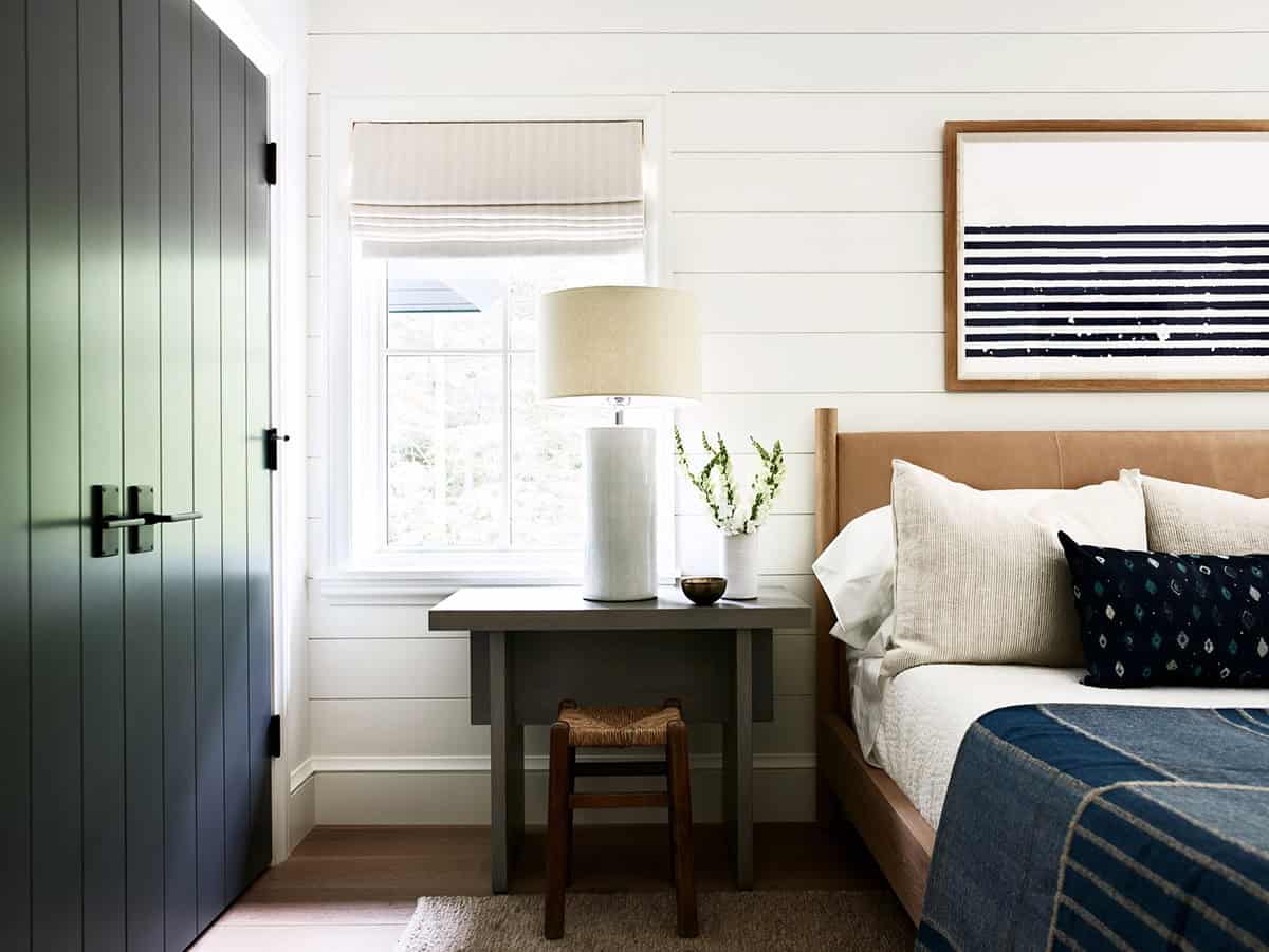 Bedroom with leather headboard, striped artwork, and dark green paneled door