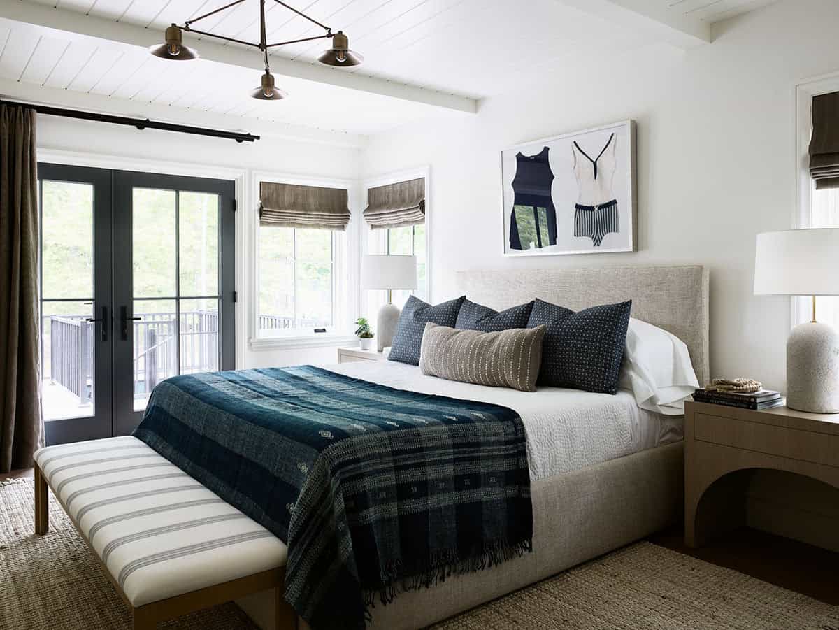 Primary bedroom with French doors, beamed ceiling, and striped upholstered bench
