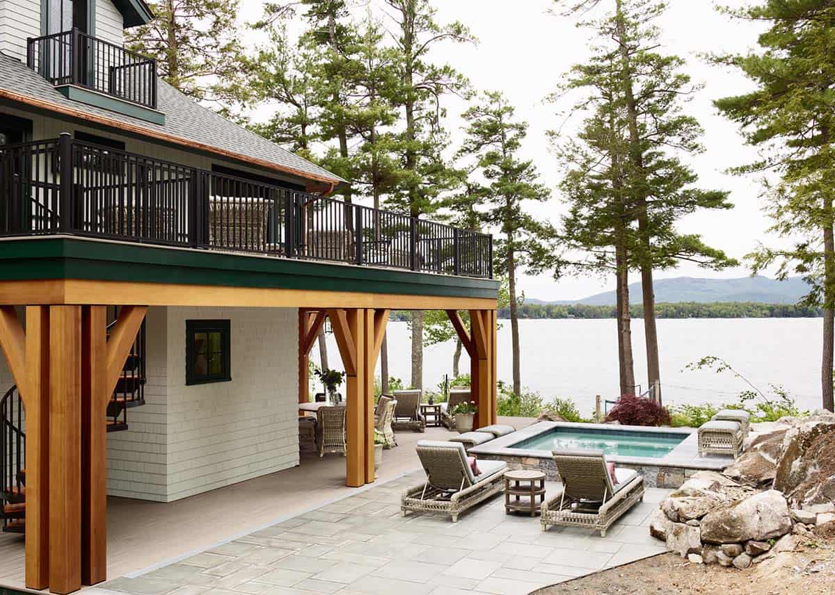 Lakeside guest house with timber columns, stone patio, and small spa