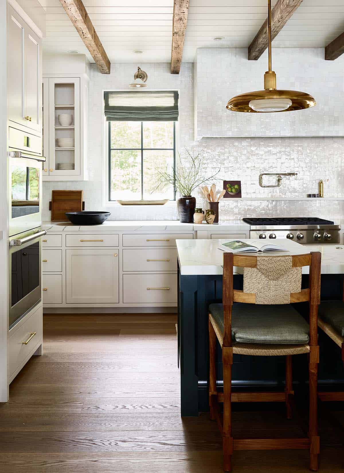 Kitchen with zellige tile backsplash, wood beams, and navy island