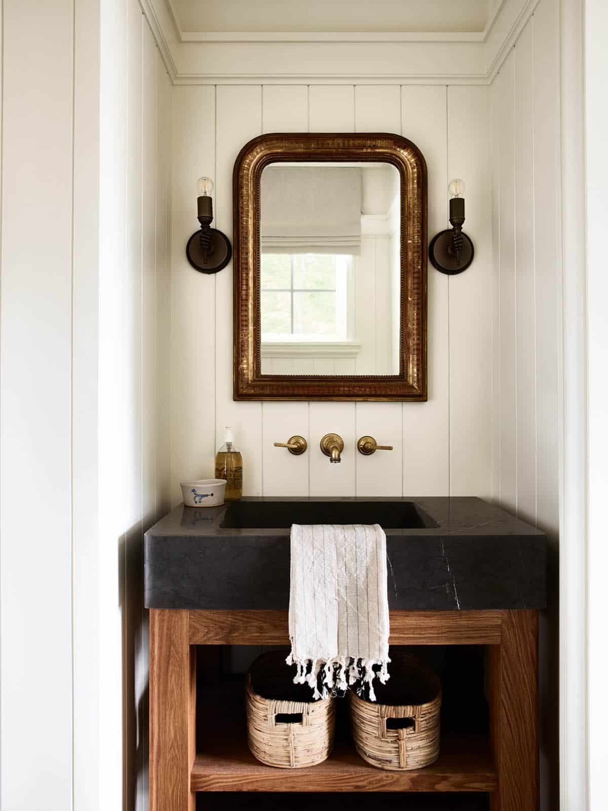 Powder room with antique gold mirror, stone sink, and open oak vanity