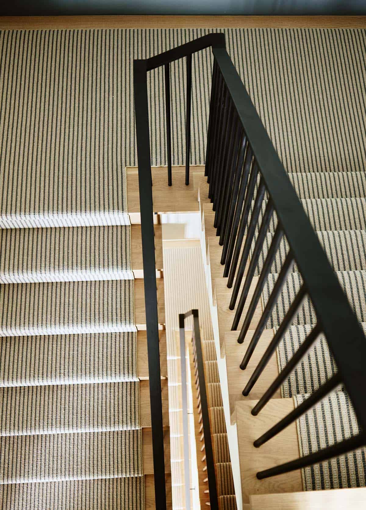 Overhead view of striped stair runner and black spindle railing