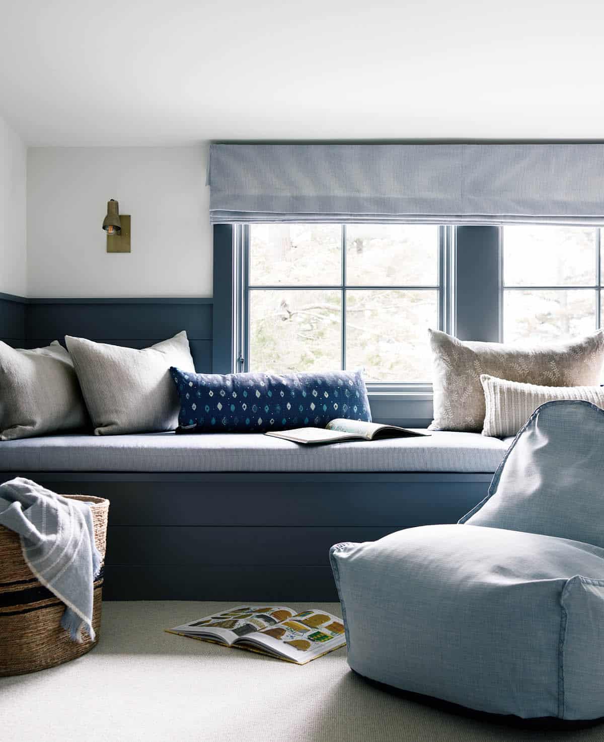 Window seat with blue cushion, patterned pillows, and light blue bean bag