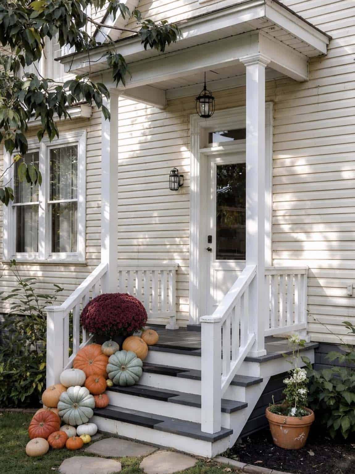 White porch steps with cascading heirloom pumpkins and a burgundy mum