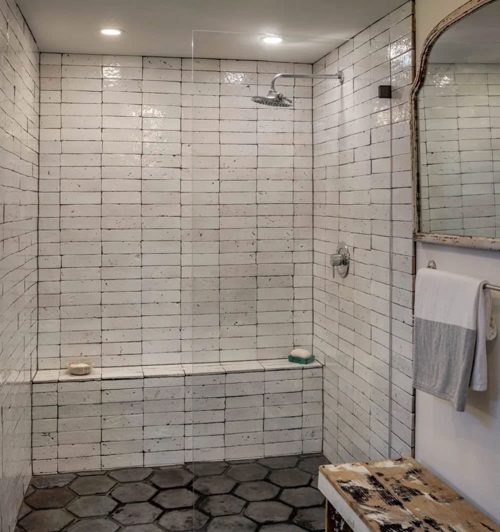 Walk-in shower with handmade white tile, built-in bench, and hexagonal floor tile