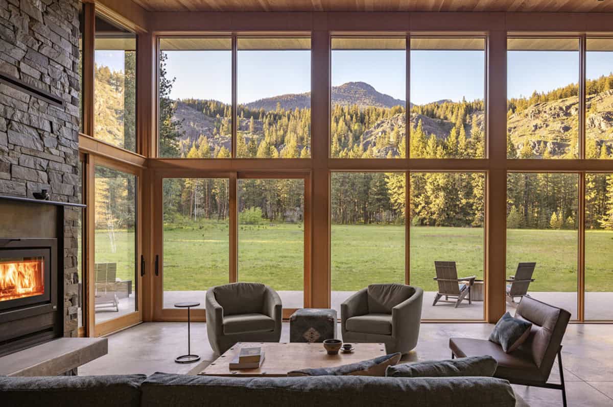 Living room with floor-to-ceiling windows framing mountain meadow view