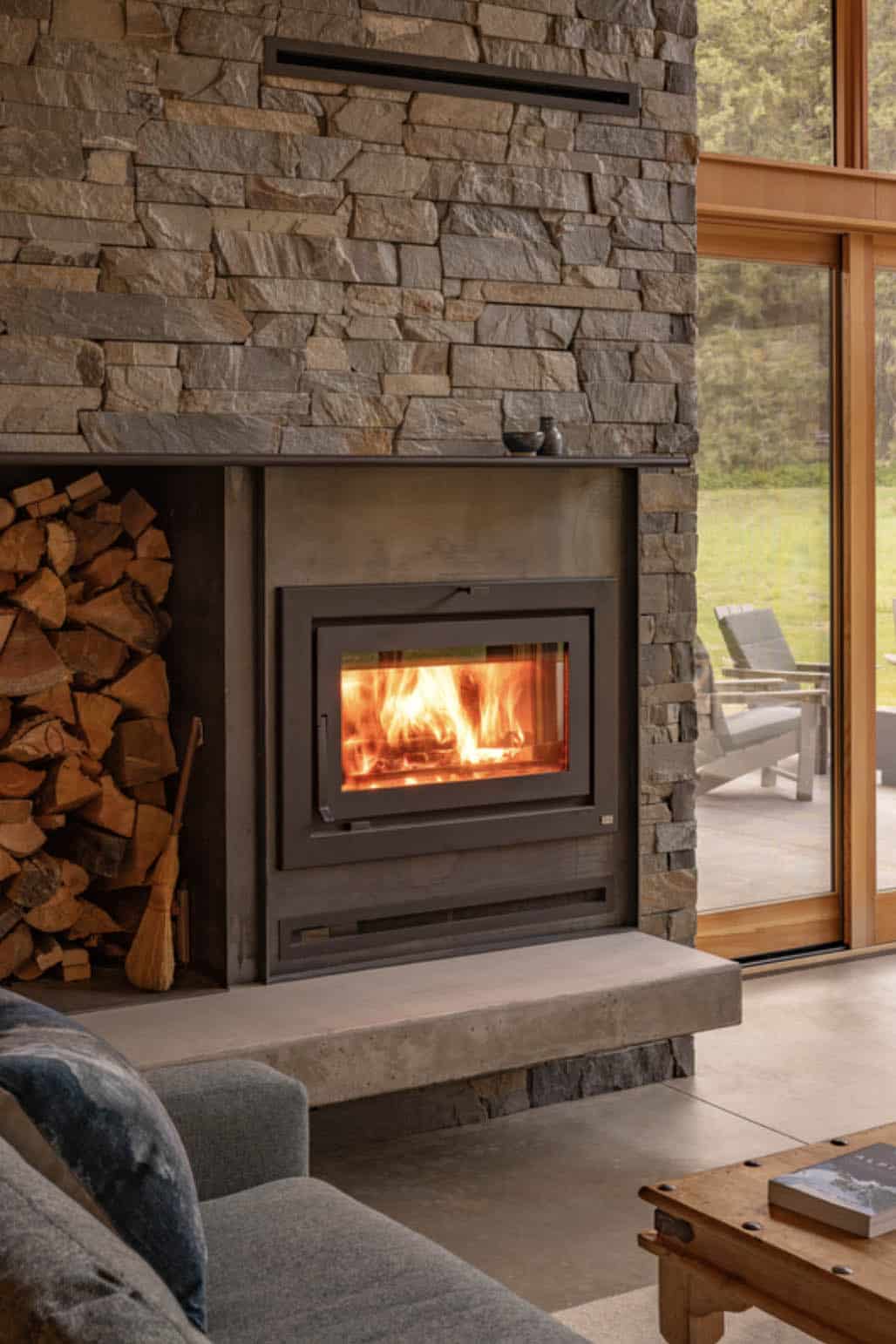 Stone fireplace with built-in firewood storage and concrete hearth