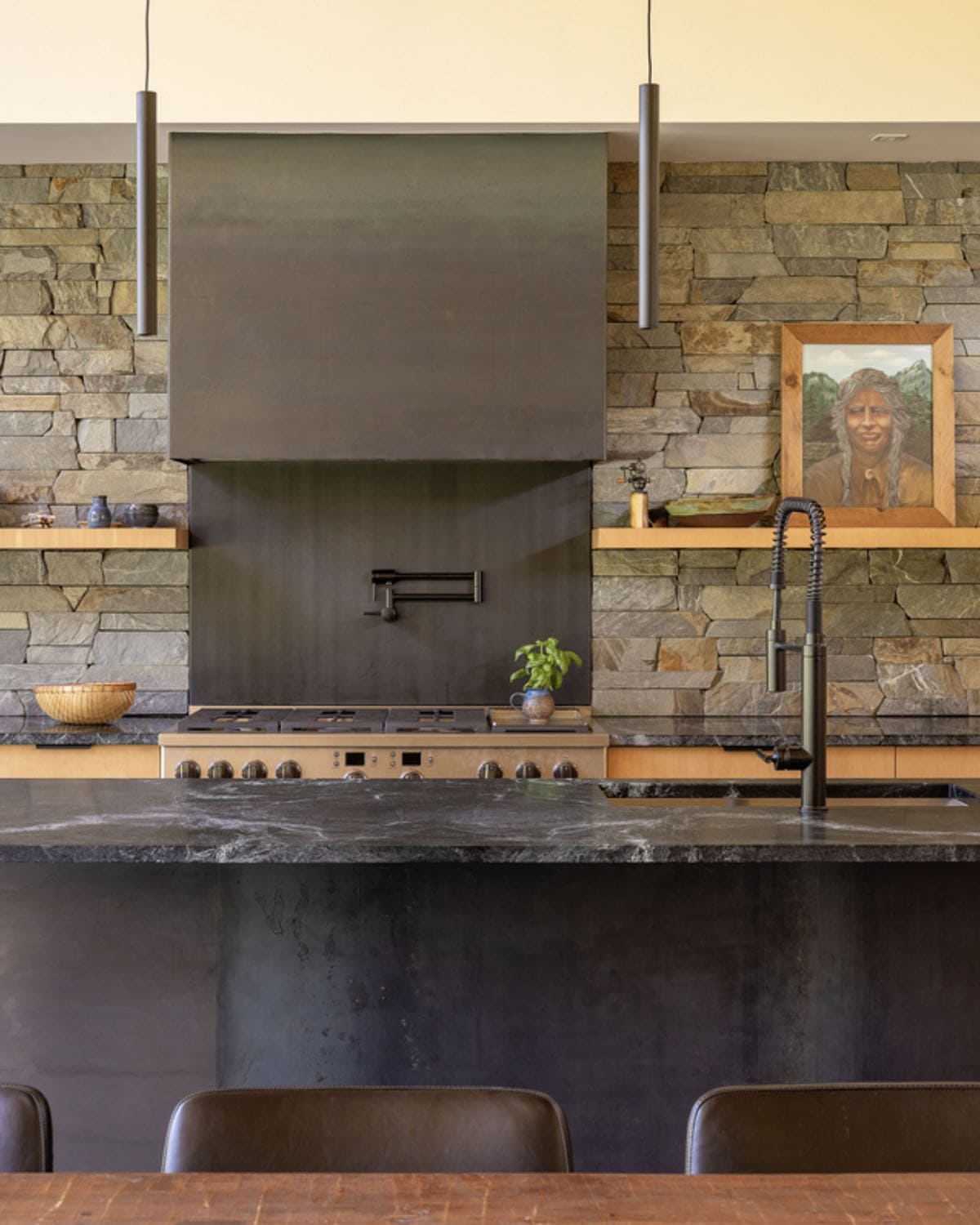 Kitchen backsplash with stone wall and blackened steel range hood