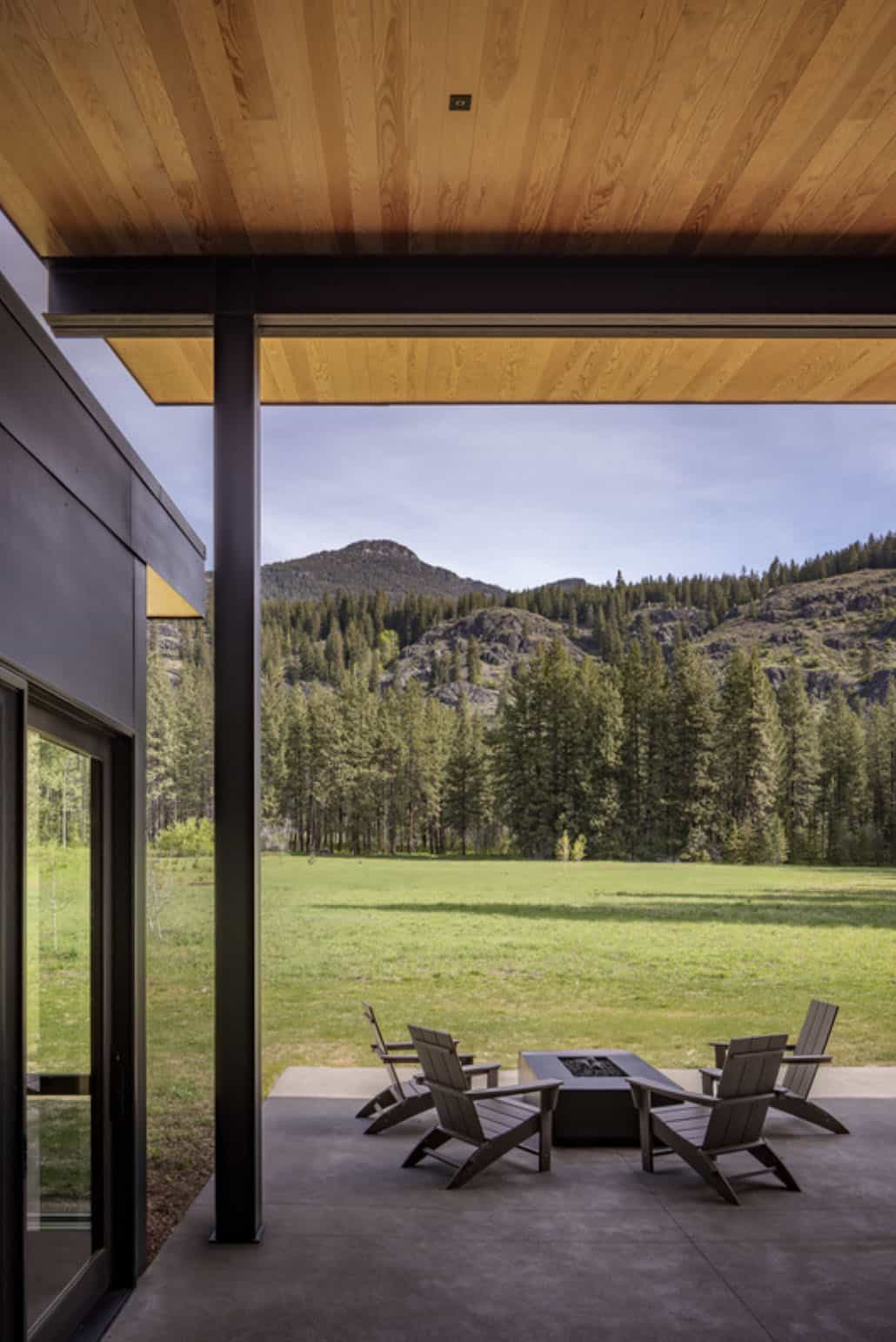 Covered patio with fire pit and chairs overlooking meadow