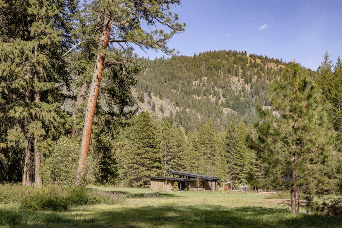 Distant view of home set against mountain and pine forest